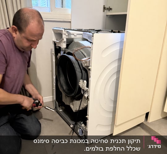 אדם מתקן מכונת כביסה עם כלים שונים
